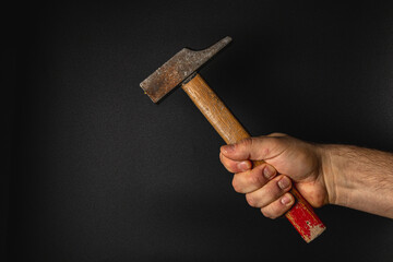 Hand holding a hammer against a dark background
