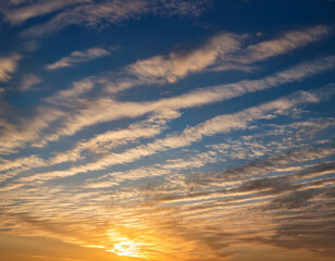 Fototapeta premium A morning sky brushed by golden sunlight shining through thin layers of high-altitude cirrostratus clouds.