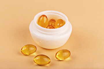 Mockup. Jar filled with omega capsules on pastel background. Capsules symbolize vitamin-enriched skincare. Omega capsules in cosmetic jar emphasize health vitamin concept for beauty care