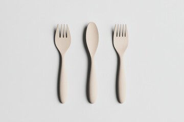 Wooden Cutlery Set.  Three simple, light beige wooden utensils two forks and one spoon, arranged symmetrically on a plain white background.