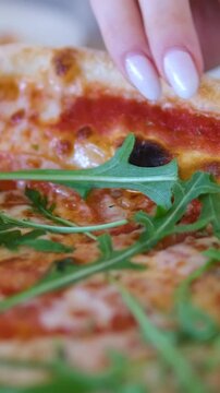 Pizza arugula hand Drizzling Extra Virgin Olive Oil on top of a Pizza