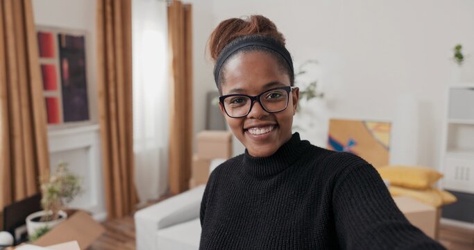 In her newly rented home, a smiling woman holds up her phone to record a vlog. She waves to the camera, gives a tour of the apartment, and talks about the moving experience.