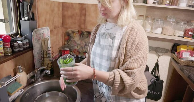 A young woman is blending a wild bear garlic in a kitchen