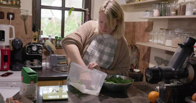 A young woman is blending a wild bear garlic in a kitchen