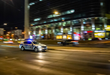 Fototapeta premium A police patrol car speeds along a Moscow street at night