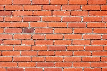 Obraz premium Weathered red brick wall with rough texture and visible mortar lines, photographed in natural light, used as an architectural or urban background. Ai generative