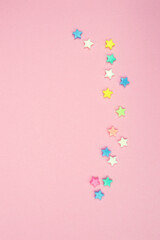 Pink background with scattered miniature stars for kids party or craft. Top view.