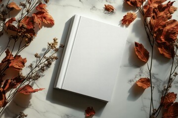 Blank book mockup features a clean design resting on a stunning surface adorned with fallen autumn leaves and dried branches
