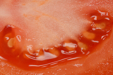 A close-up shot of a halved tomato revealing its juicy flesh, seeds, and texture