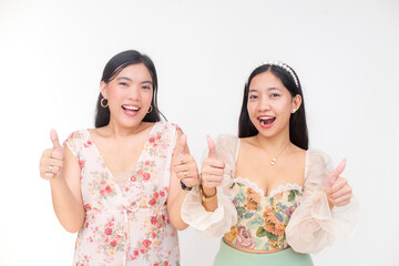 Young Filipino women smiling brightly while showing thumbs up hand gestures, wearing trendy floral tops and radiating confidence in a white background.