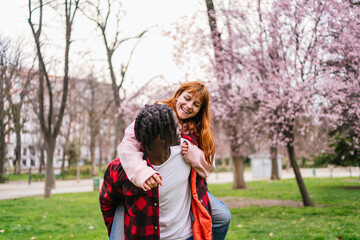 Fototapeta premium Interracial couple having fun in blooming park during springtime