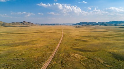 Wide open road stretching through the heart of the mongolian steppe under a clear blue sky