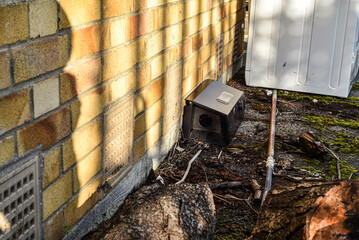Black rodent bait and trap station being used outside a building to control rats.