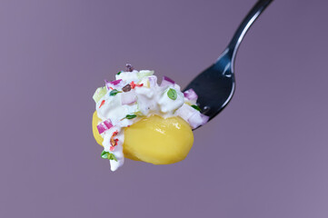 Fresh curd cheese with herbs, cucumber and onion on a potato