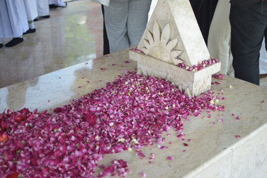 a marble tomb decorated with pink and white flower petals, with people standing nearby.
