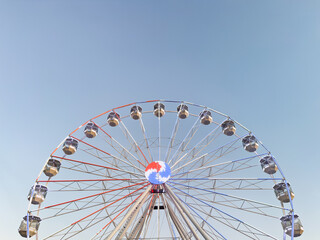 colorful illuminated Ferris wheel against clear blue sky. amusement ride at fairground. modern entertainment attraction with colorful lights. urban fun