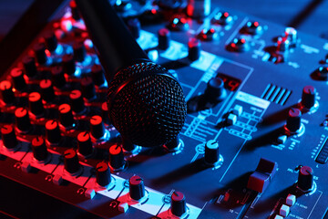 Professional mixing console with microphone on table in neon lights, closeup