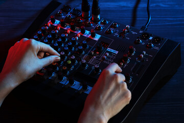 Woman working with professional mixing console at wooden table, closeup