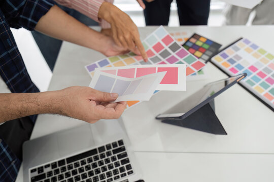 Collaboration and Creative Review. Diverse team discussing color palettes and design elements in a modern workspace.