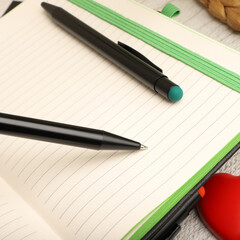 Two black pens resting on an open notebook, ready for writing