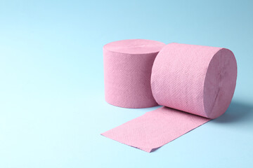 Pink toilet paper rolls on light blue background, space for text