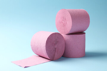 Pink toilet paper rolls on light blue background