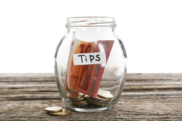 Glass jar with tips on wooden table against white background