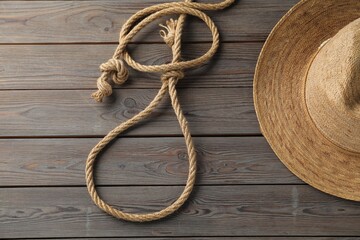 Obraz premium Lasso made of cotton rope and straw hat on wooden background, flat lay