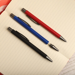 Naklejka premium Elegant Pen Standing on Open Notebook with Vivid Decorative Backdrop, concept idea photo. Study desk image, top view.