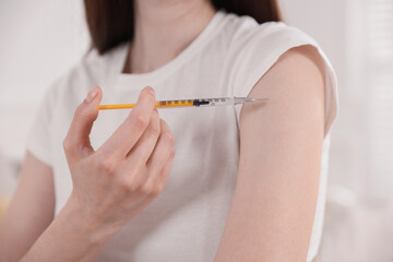 Woman making insulin injection into her arm indoors, closeup. Diabetes