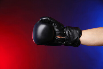 Man with boxing glove fighting on dark background in neon lights, closeup