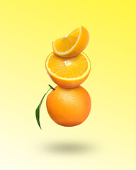 Fresh juicy oranges with green leaf falling on gradient yellow background