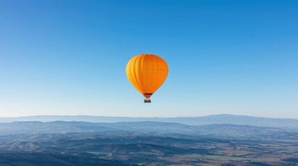 Obraz premium A vibrant orange hot air balloon soars above a breathtaking landscape
