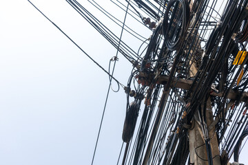 Obraz premium Dense Network of Power Lines and Cables Against a Gray Sky