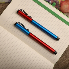 Elegant Pen Standing on Open Notebook with Vivid Decorative Backdrop, concept idea photo. Study desk image, top view.