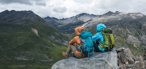 Two hiking friends enjoy the view on high altitude mountain top