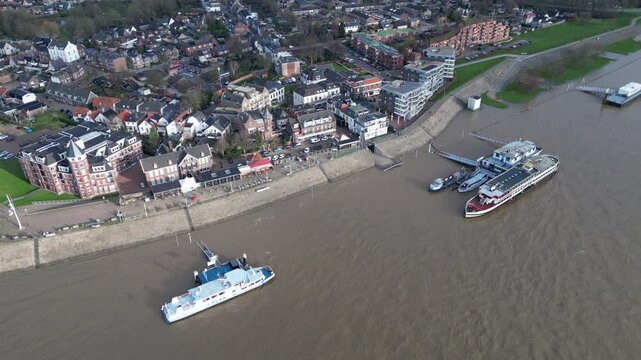 Tilting drone shot of vessels moored at shores of Tolkamer, with submerged quay, during period of high water levels in the Netherlands
