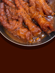 Dim sum chicken feet with black pepper seasoning on a brown background.