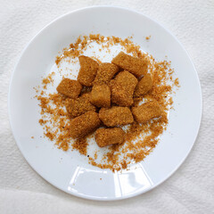 A pile of mochi sprinkled with ground peanuts served on a white plate. Japanese snack food.
