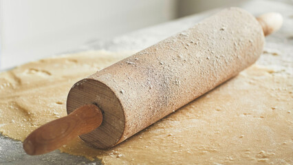 Closeup of wooden rolling pin covered in flour.