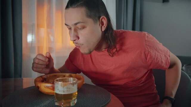 Man enjoying a delicious meal and drink while seated at a table in a cozy indoor setting during the evening