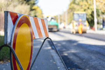 Construction work on urban street with safety barriers and machinery in action during sunny autumn...