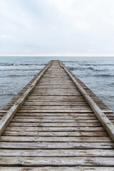 Fototapeta premium Wooden pier leading to the Adriatic Sea on a cloudy autumn beach in Italy