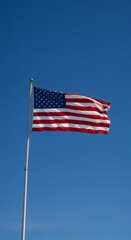 Fototapeta premium American flag unfurls against a pristine azure sky, freedom's iconic symbol