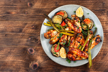 Spicy grilled chicken wings on wooden surface.