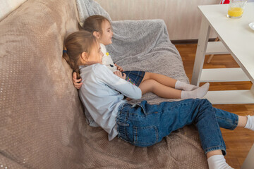 The children have eaten fruit and are relaxing on the sofa in the living room.