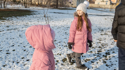Grandfather walks with his granddaughters after school in the park in sunny winter day