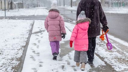 Little girls walking with his grandmother in the snow in winter