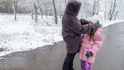 Grandmother with little girl granddaughter on snowy weather outdoors.