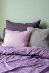 A bed with a purple comforter and pillows. The pillows are purple and gray, and they are arranged in a way that creates a cozy and inviting atmosphere. The bed is neatly made
